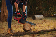 Photo of CRAFTSMAN CMCCS620M1 cordless chainsaw cutting wood outdoors, held by person wearing gloves.