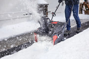 Photo of CRAFTSMAN snow blower, SKU CMXGBAM1054539, clearing snow from a driveway with a person operating it.
